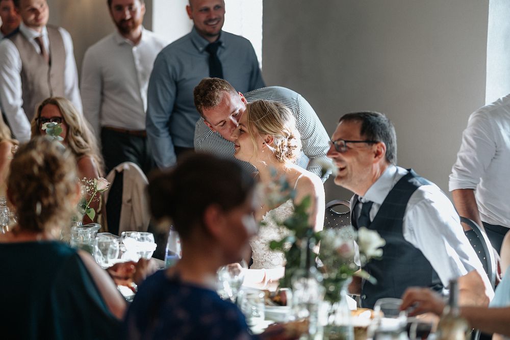 Guests enjoying conversation and drinks at an elegant indoor wedding reception dinner table.
