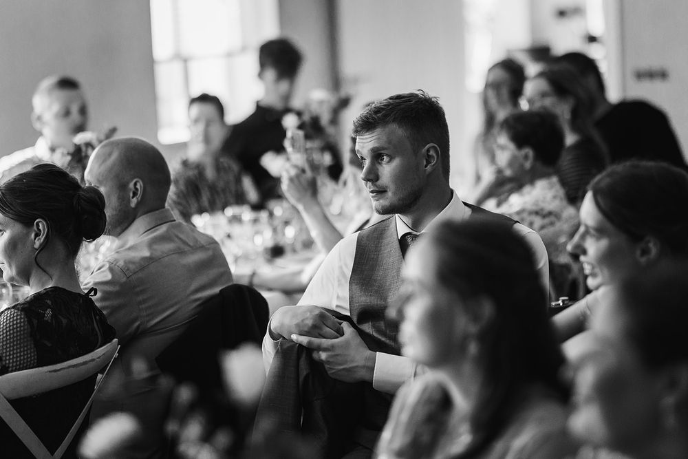 Wedding guests seated in rows watching the ceremony in a bright indoor venue.