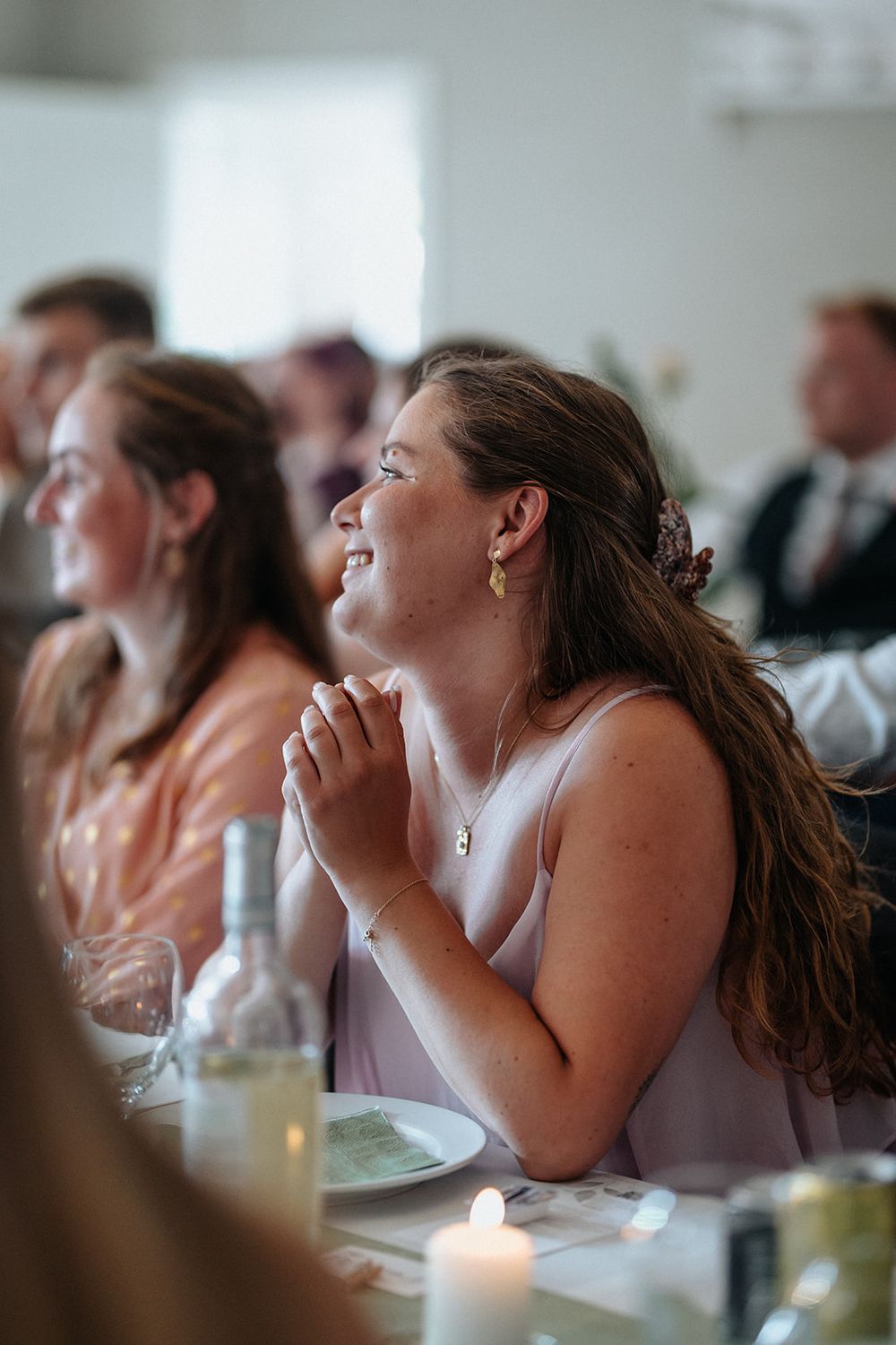 Wedding guests share joyful laughter during a candlelit reception dinner.