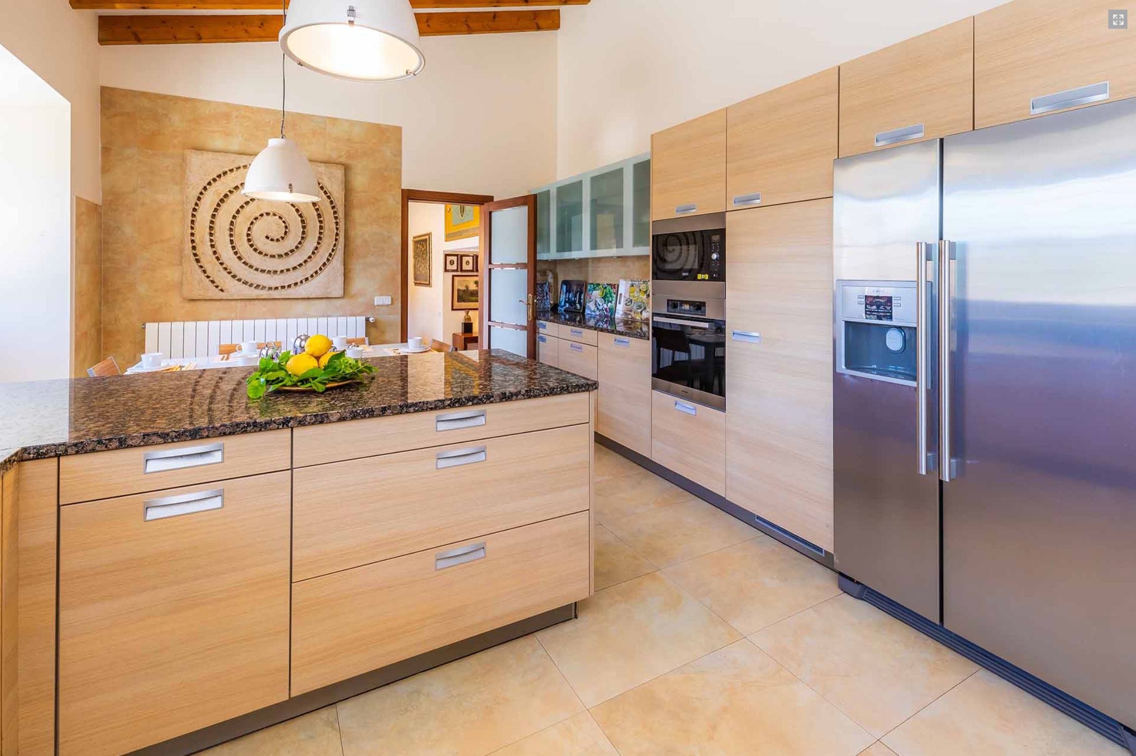 Modern kitchen interior with wooden cabinets, stainless steel appliances and exposed wooden ceiling beams.