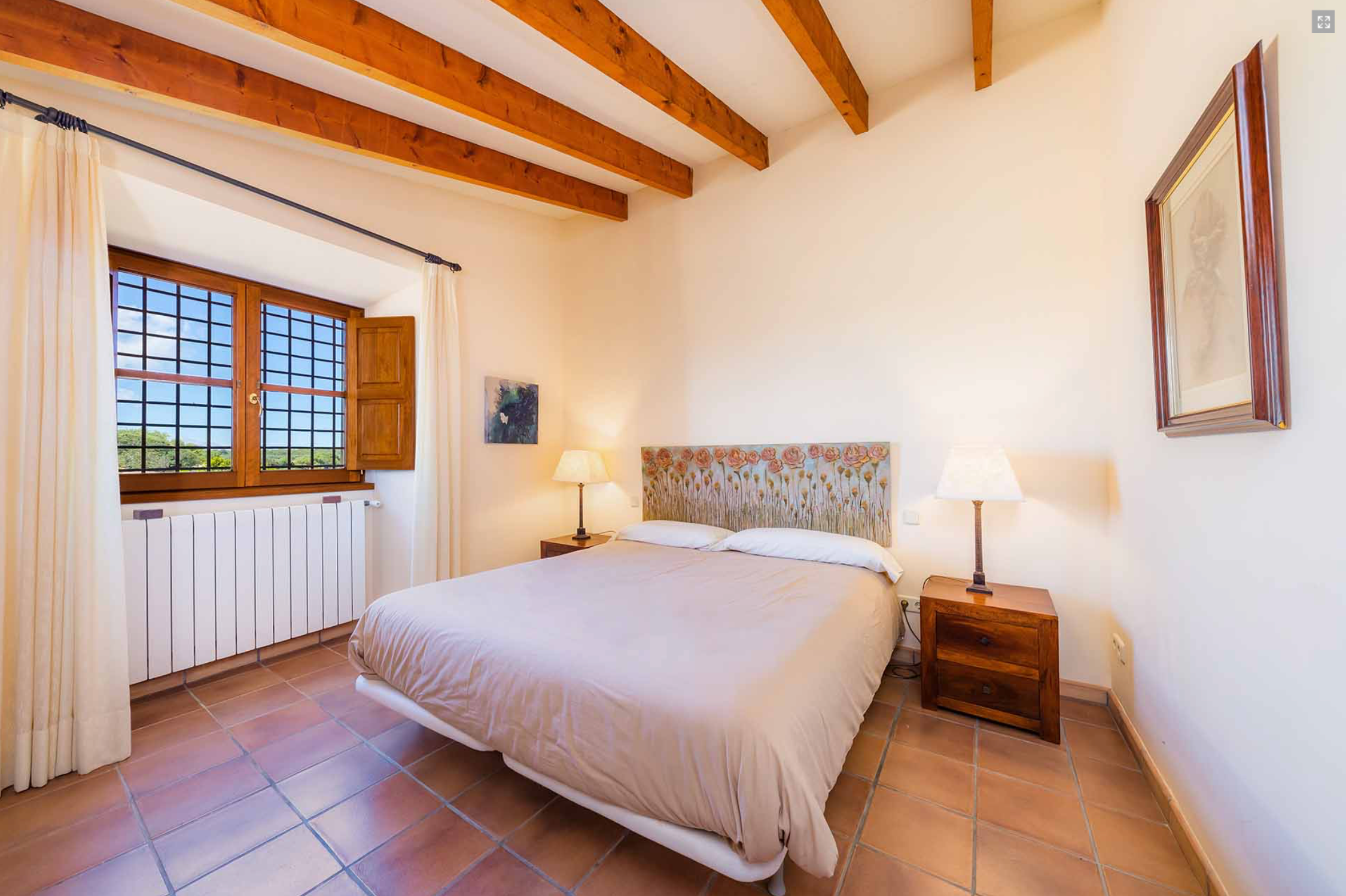 Interior panoramic view of a rustic bedroom with exposed wooden beams and terracotta floor tiles.