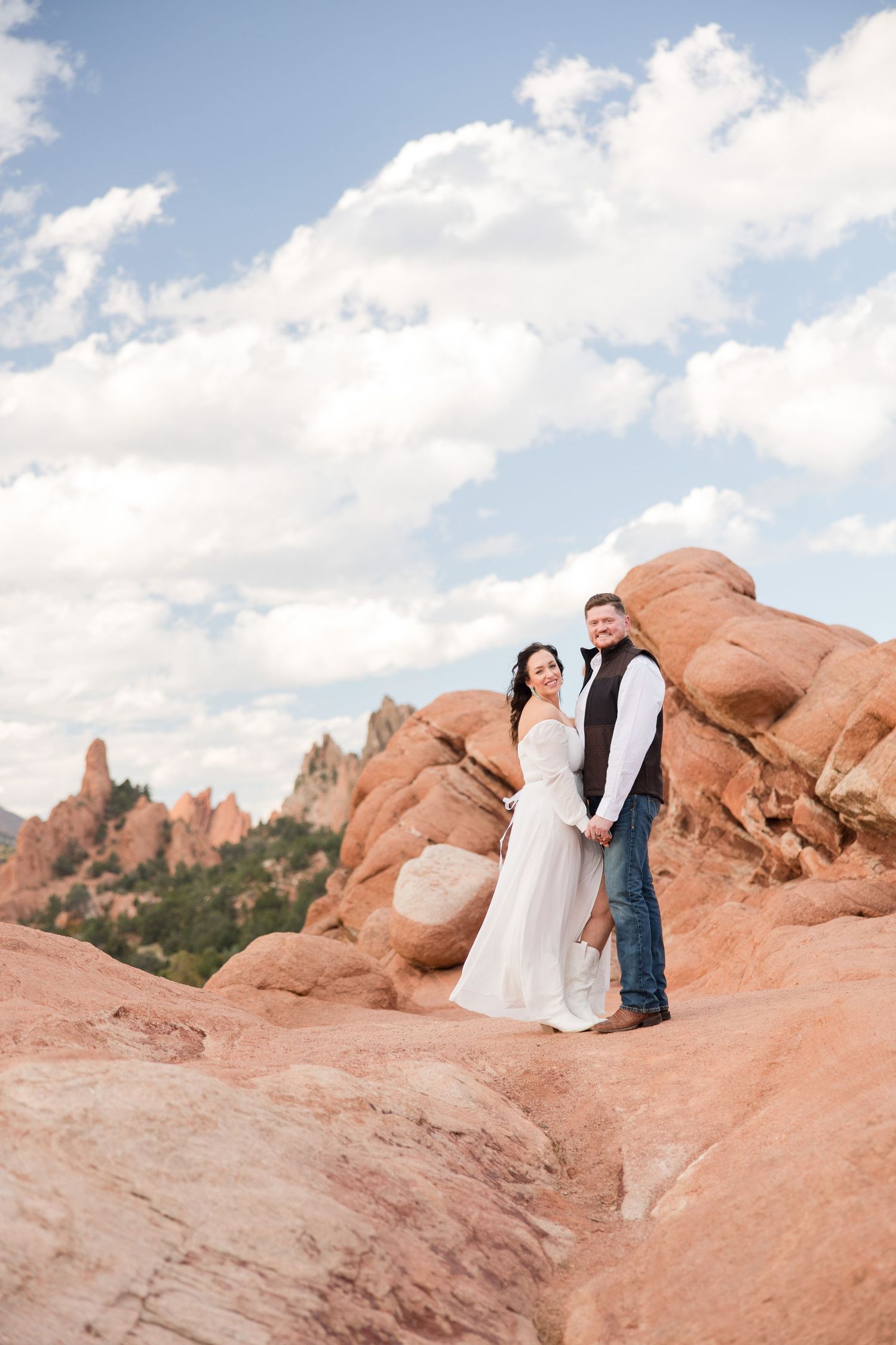 Romantic couple embraces in scenic mountain landscape during sunset engagement photoshoot.