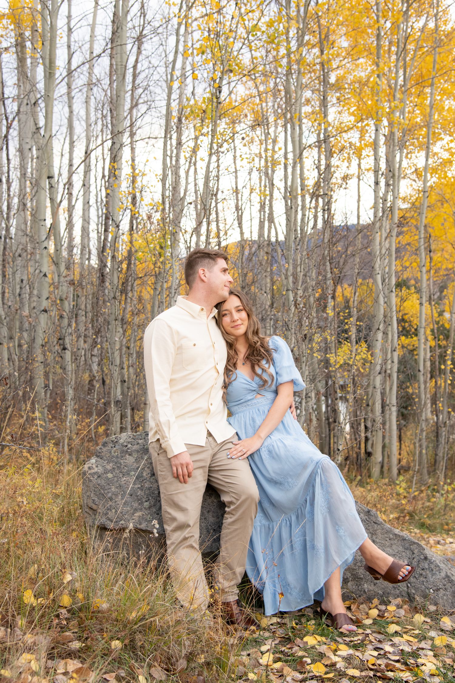 Vail engagement photos with  couple in coordinated outfits poses together among golden aspen trees during an autumn photo session in nature.