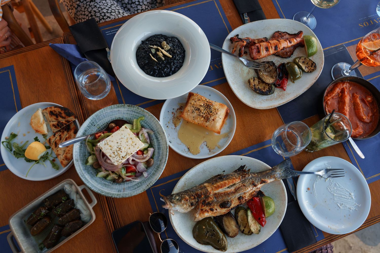 A table filled with various seafood dishes including lobster, fish, and appetizers on white plates at a restaurant.