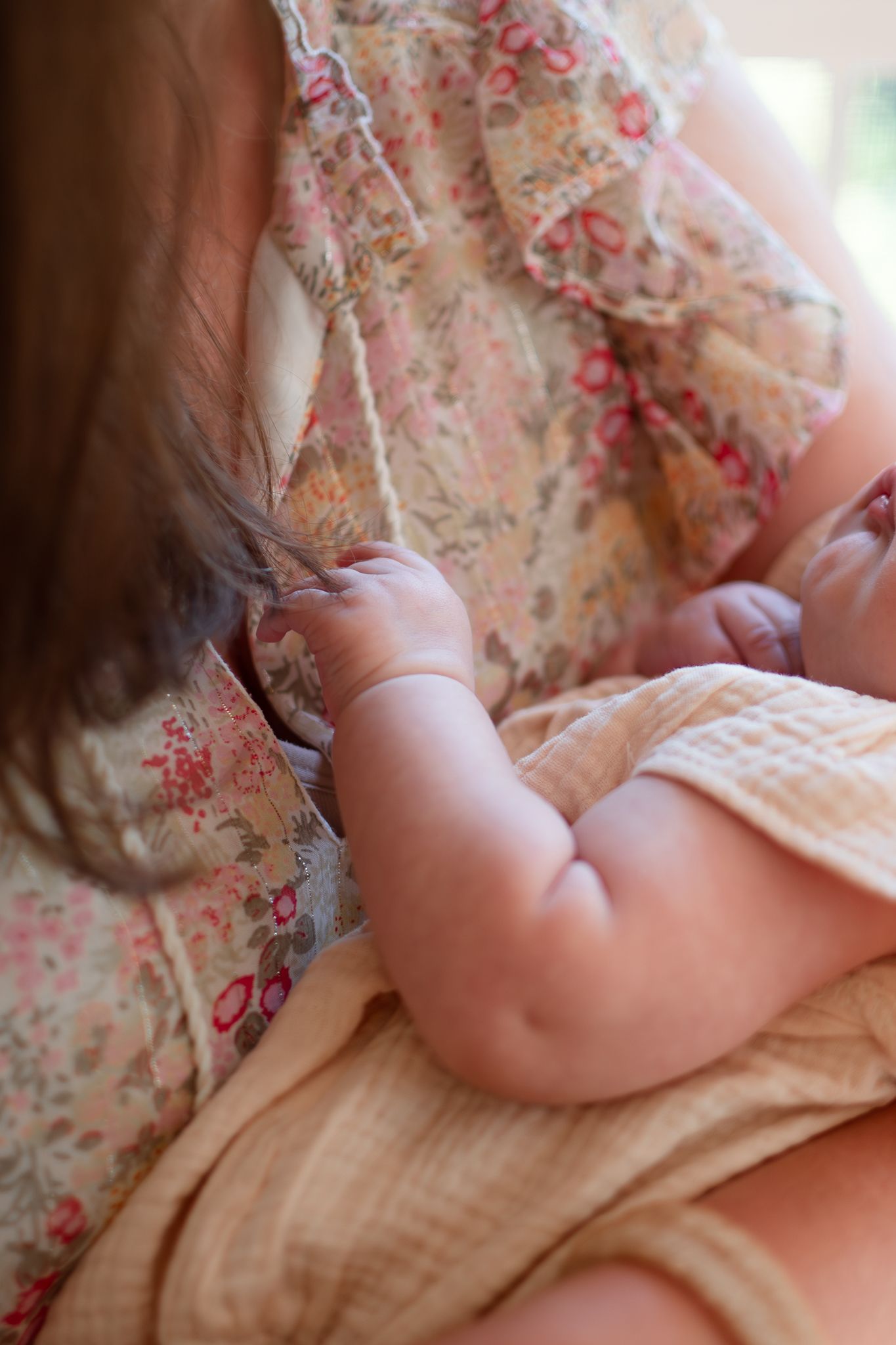 A baby lies peacefully on floral patterned bedding in a series of soft, dreamy photographs.