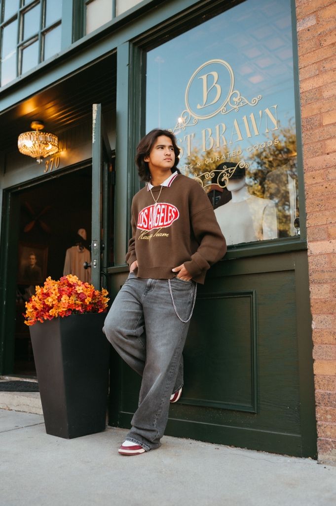An elegant storefront with autumn decorations and gold lettering on black doors.