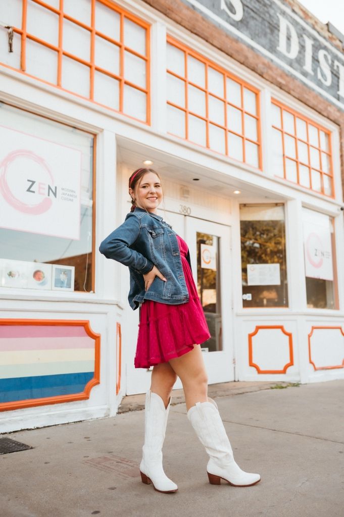 Street style photo showcasing western boots and red dress combination against modern storefront.