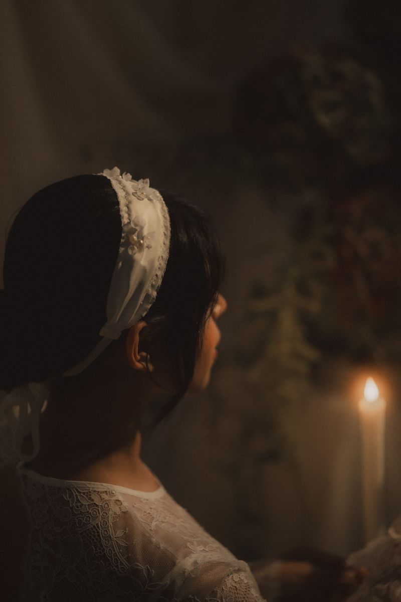 A series of moody candlelit portraits showing the back of a person in white lace against a dark background.