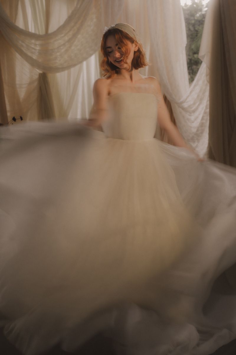 A bride in a flowing white ballgown twirls gracefully, creating a dreamy motion effect with the tulle skirt.