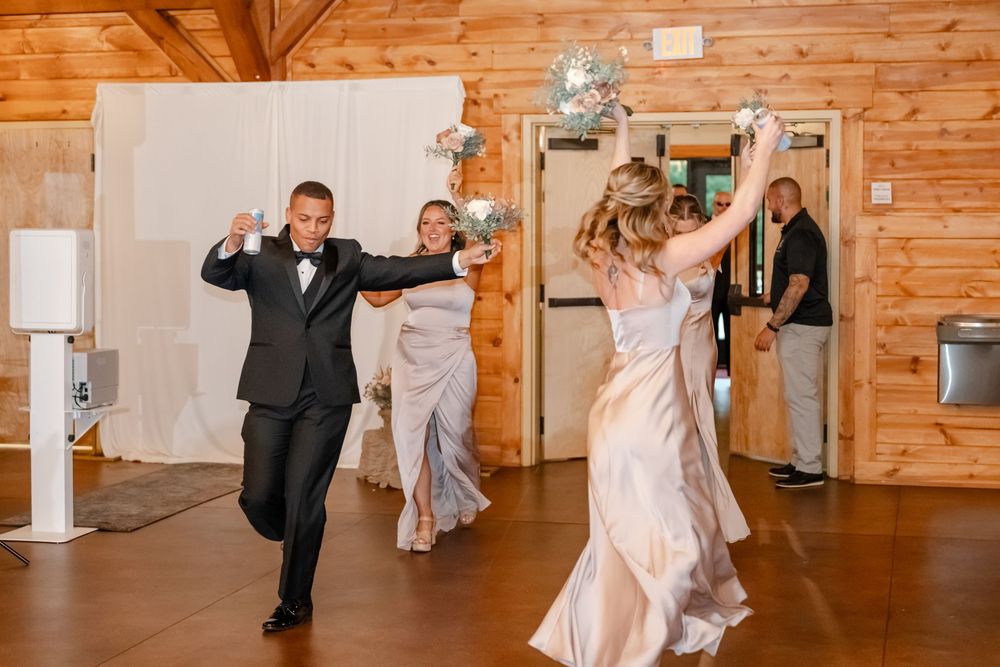 Wedding guests dancing joyfully in a rustic wooden venue with disco ball decorations during a reception celebration.