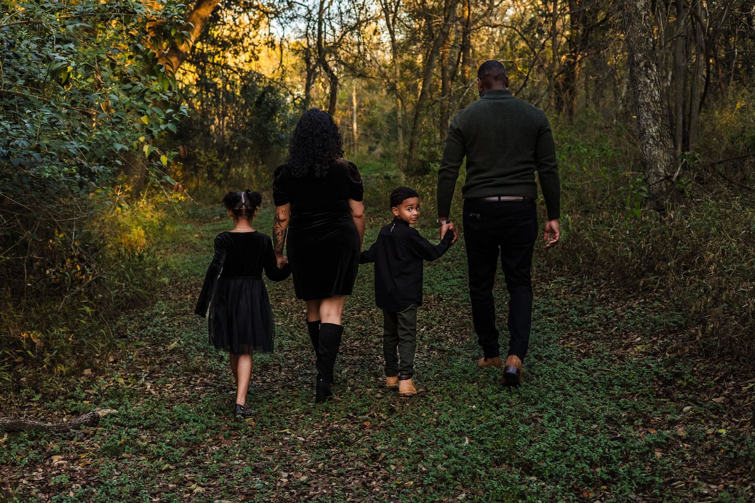 Documentary-style family portrait of a mother, father, and two children walking through a wooded Central Texas trail during a lifestyle sess