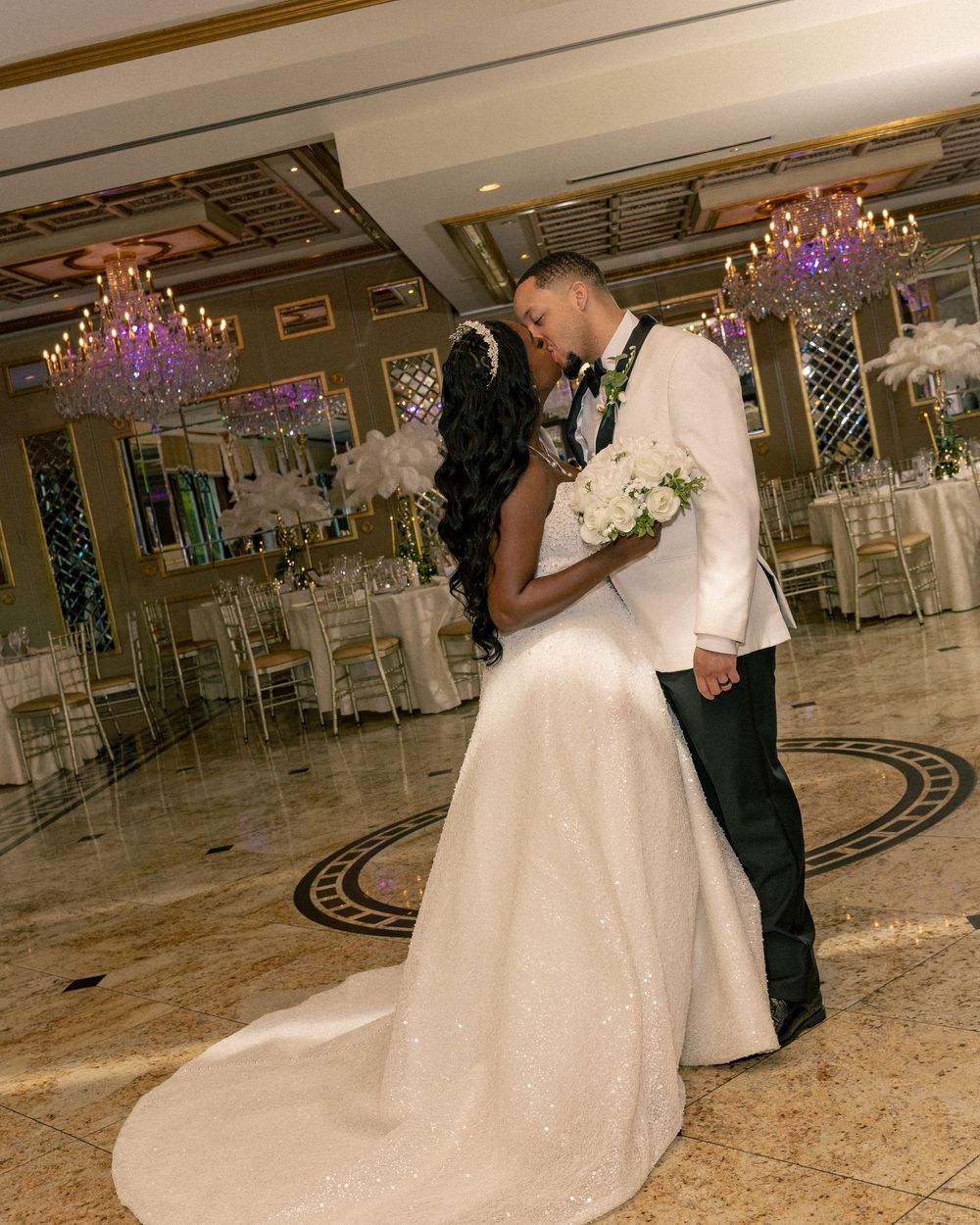 Bride and groom share a romantic kiss on the dance floor of an elegant wedding reception venue.