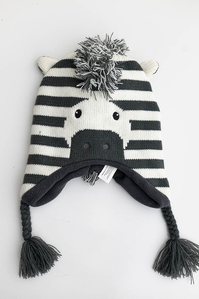Black and white striped zebra animal knit baby hat with pom-pom and braided tassels.