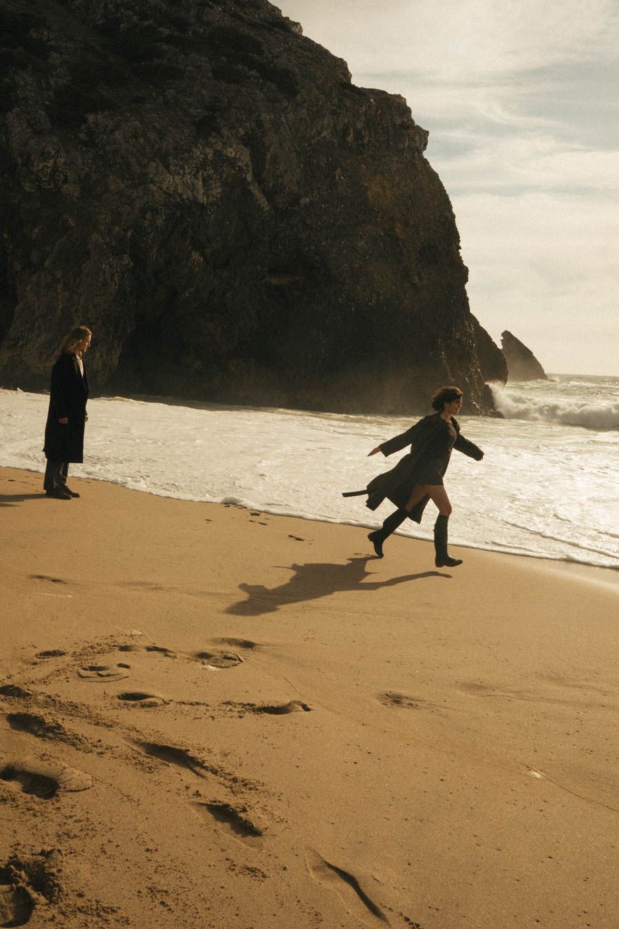 Couple running from the waves on the beach in Portugal