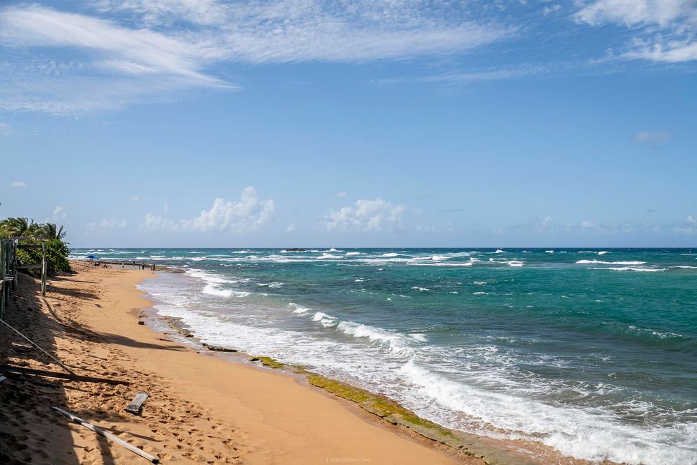 Turquoise waves washing onto a sandy beach under blue skies in Puerto Rico on a sunny day.