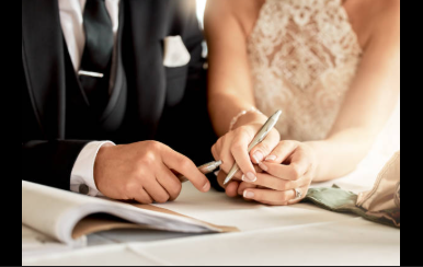 Bride and groom signing wedding certificate at altar, close-up of hands holding pen during marriage ceremony.
