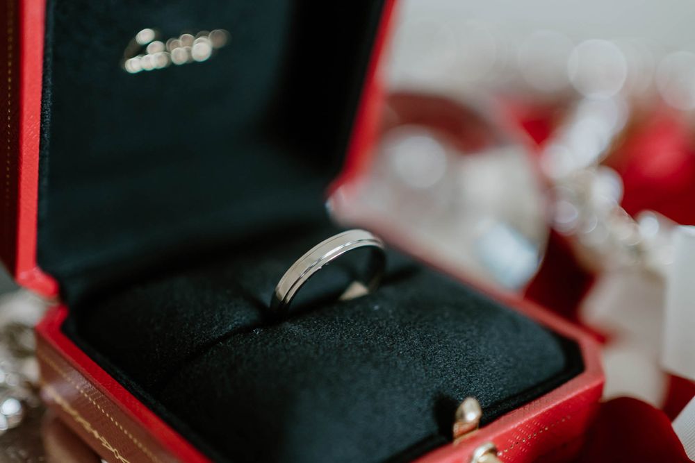 Silver wedding band displayed in a red Cartier jewelry box with black velvet cushion.