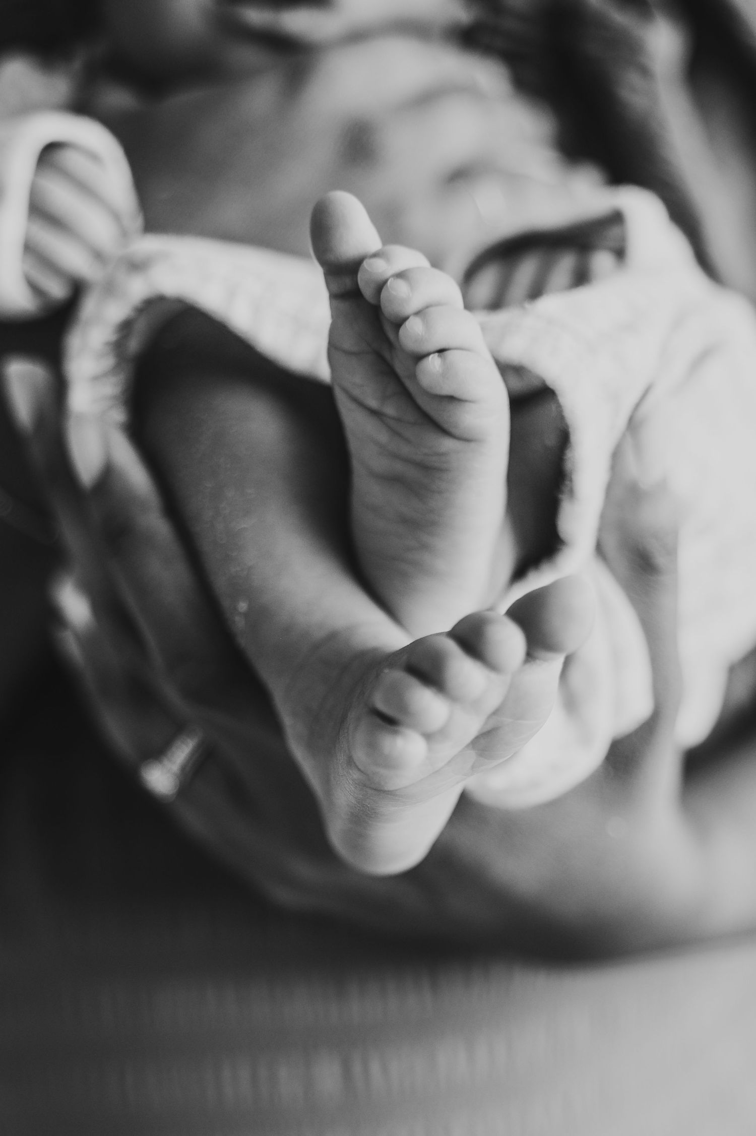 Mississauga newborn photographer captures details of a newborn baby's feet while being held by mom.