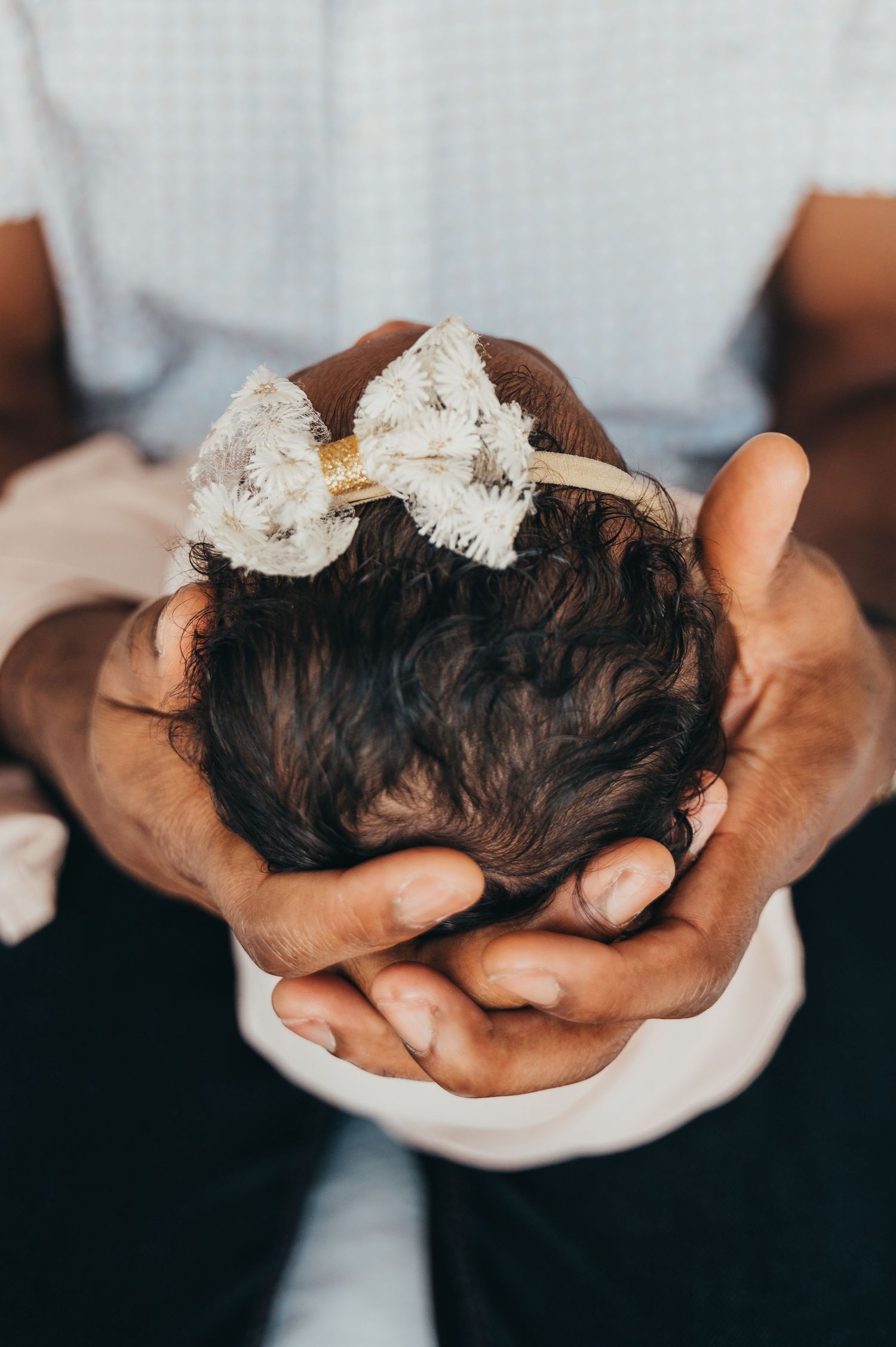 Mississauga family photographer captures dad cradling newborn baby's head with a bow