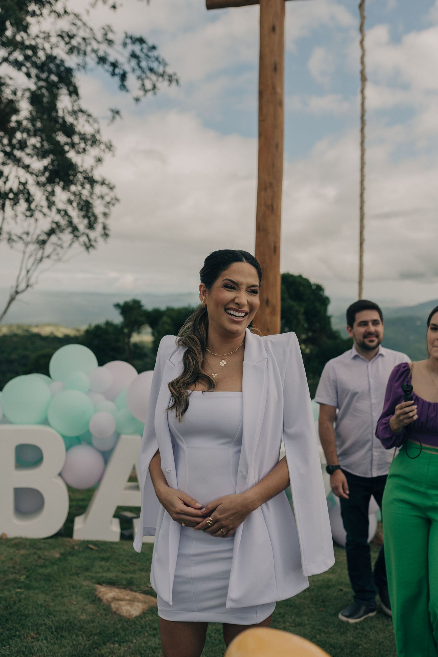Expectant couple at outdoor baby shower with white and mint balloon decorations.