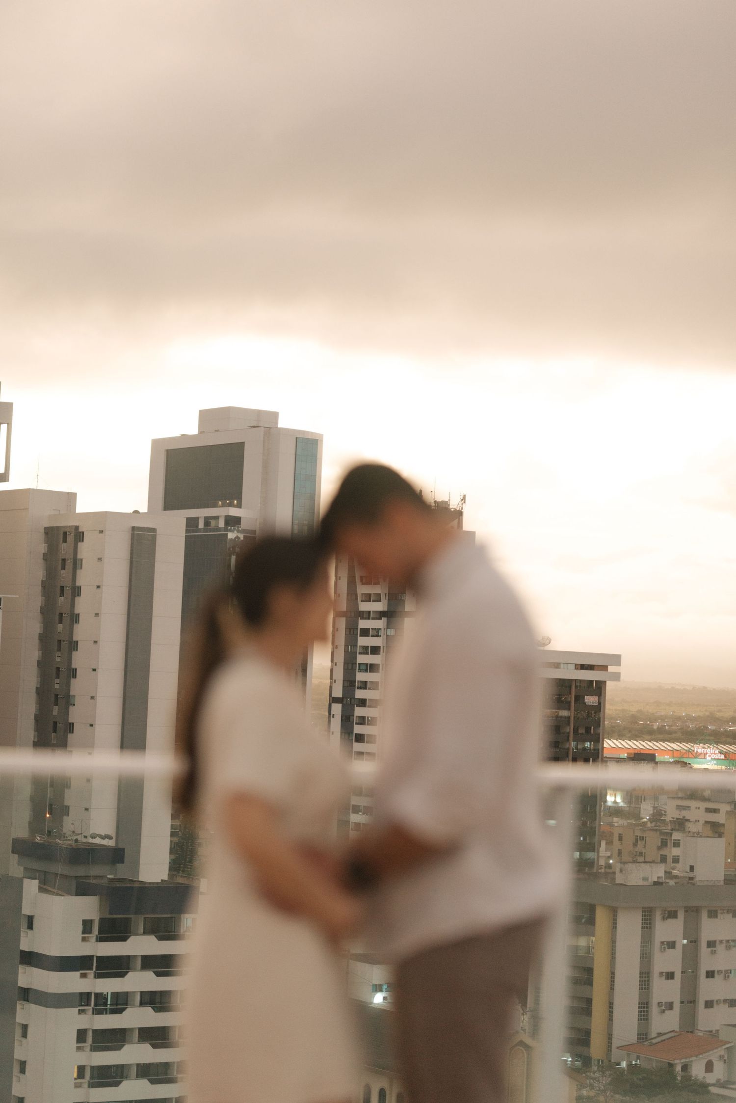 Romantic couple silhouette against city skyline at sunset.