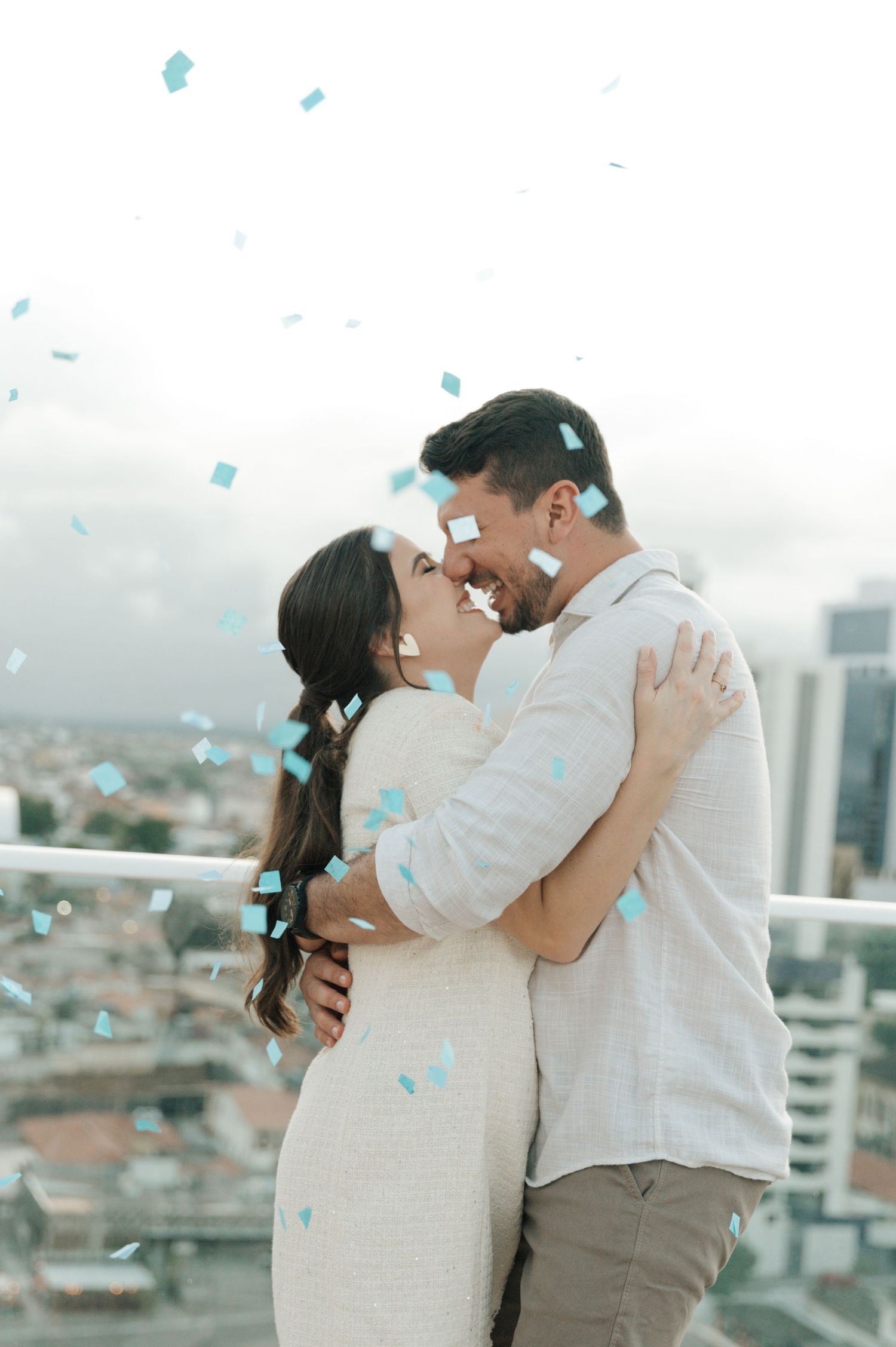 A romantic moment with blue confetti falling against a cityscape backdrop.