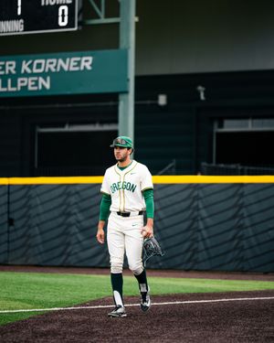 Oregon Ducks baseball pitcher stands on field in white and green uniform during a game at PK Park.