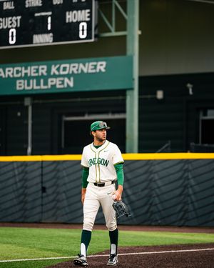 Oregon Ducks baseball player standing on field in green and white uniform at PK Park stadium.