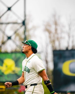 Oregon Ducks baseball player in green cap and uniform looks up during a game at PK Park.