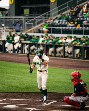 Baylor Bears baseball player stands at home plate holding a bat while a catcher crouches nearby during a college game.