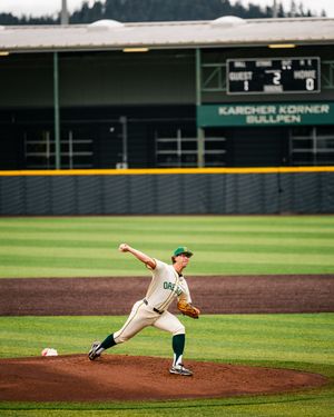 Oregon Ducks pitcher winds up to throw during a college baseball game at a green stadium.