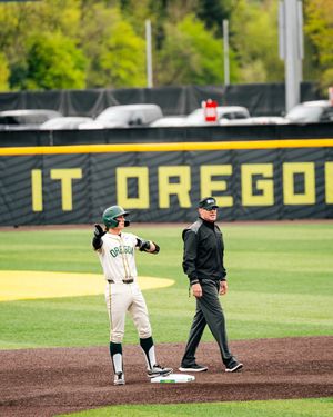Oregon Ducks baseball player celebrates at second base with an umpire standing nearby at PK Park.