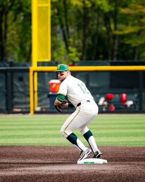 Oregon Ducks baseball player in white and green uniform fielding at second base during a college game.