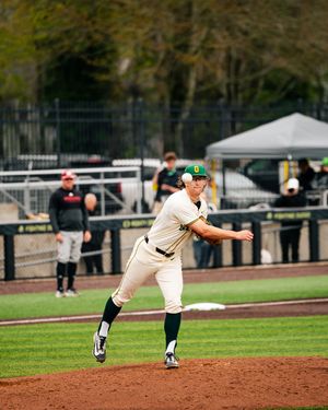 Oregon Ducks baseball pitcher mid-windup on the mound during a college baseball game in green and white uniform.