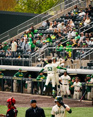 Oregon Ducks baseball player #53 celebrates at dugout as teammates cheer during a college baseball game.