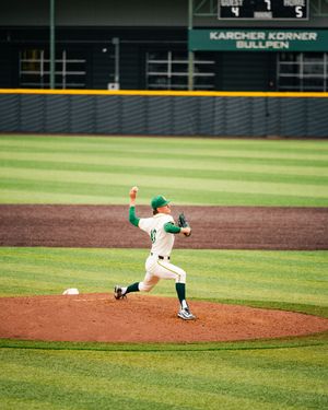 Baseball pitcher in green and white uniform mid-throw on the mound at Karcher Korner Bullpen stadium.