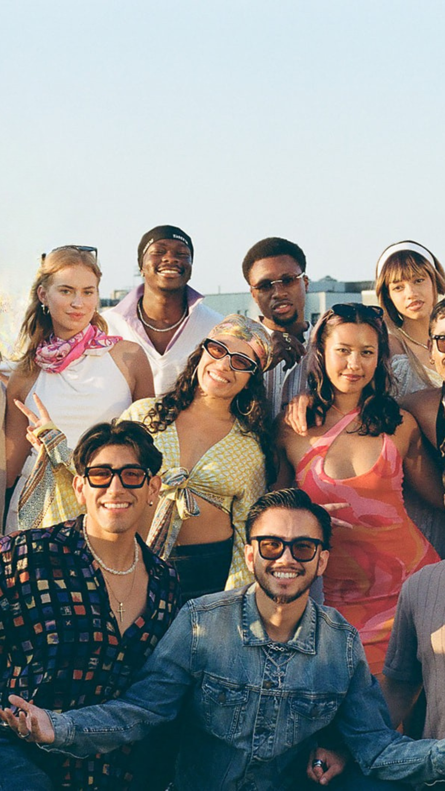 Group of diverse young friends smiling together outdoors at a sunny social event.
