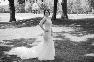Elegant bride poses in a fitted lace wedding gown with a train in a black and white photo.