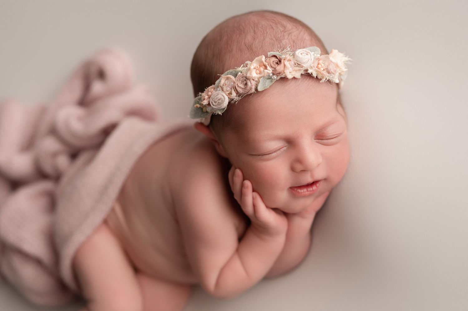 Peaceful sleeping baby girl wearing a delicate floral headband, posed on a soft pink blanket photographed in my pittsburgh newborn studio