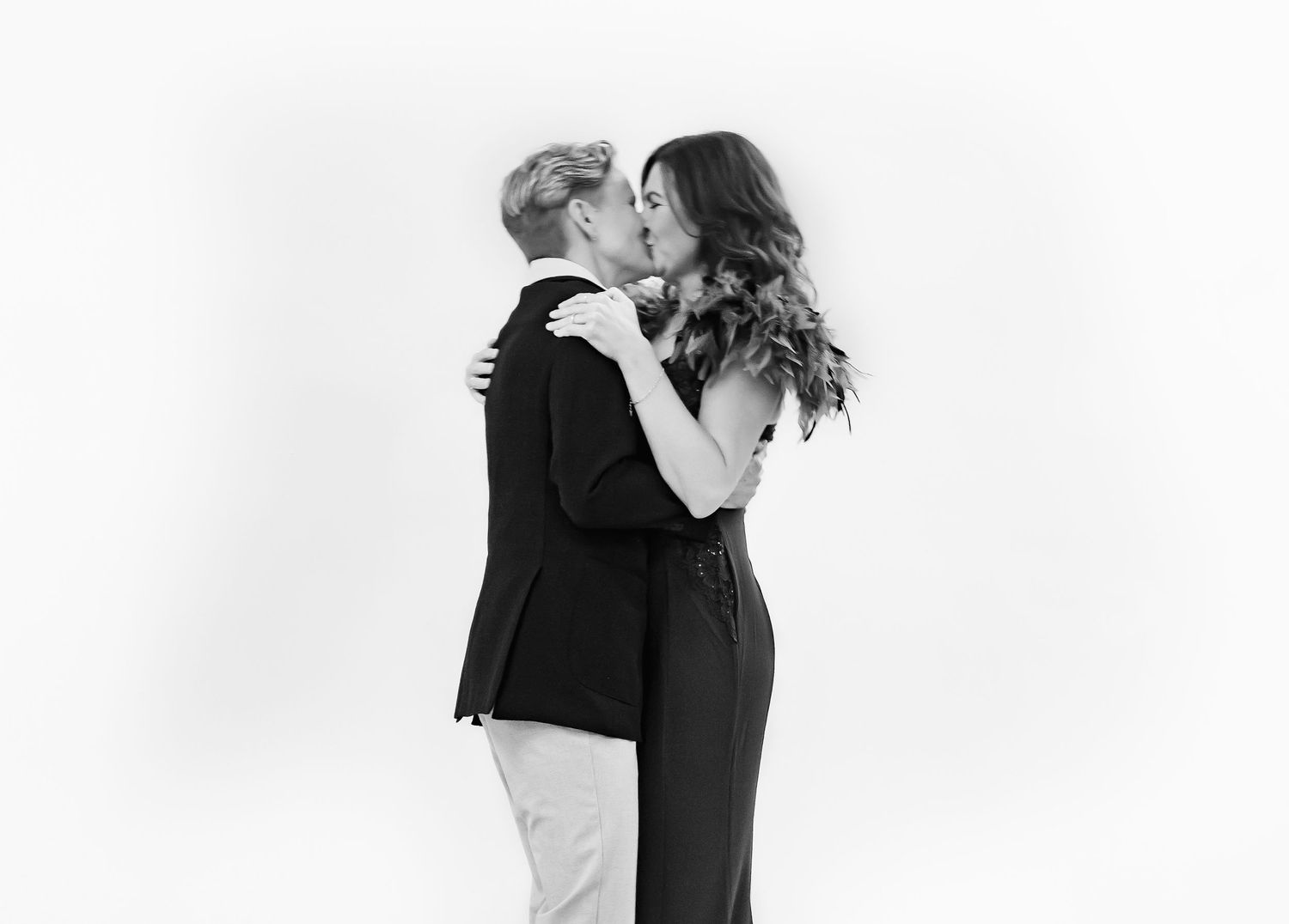 Black and white editorial wedding photo of a romantic embrace between a couple in formal attire during an intimate moment.