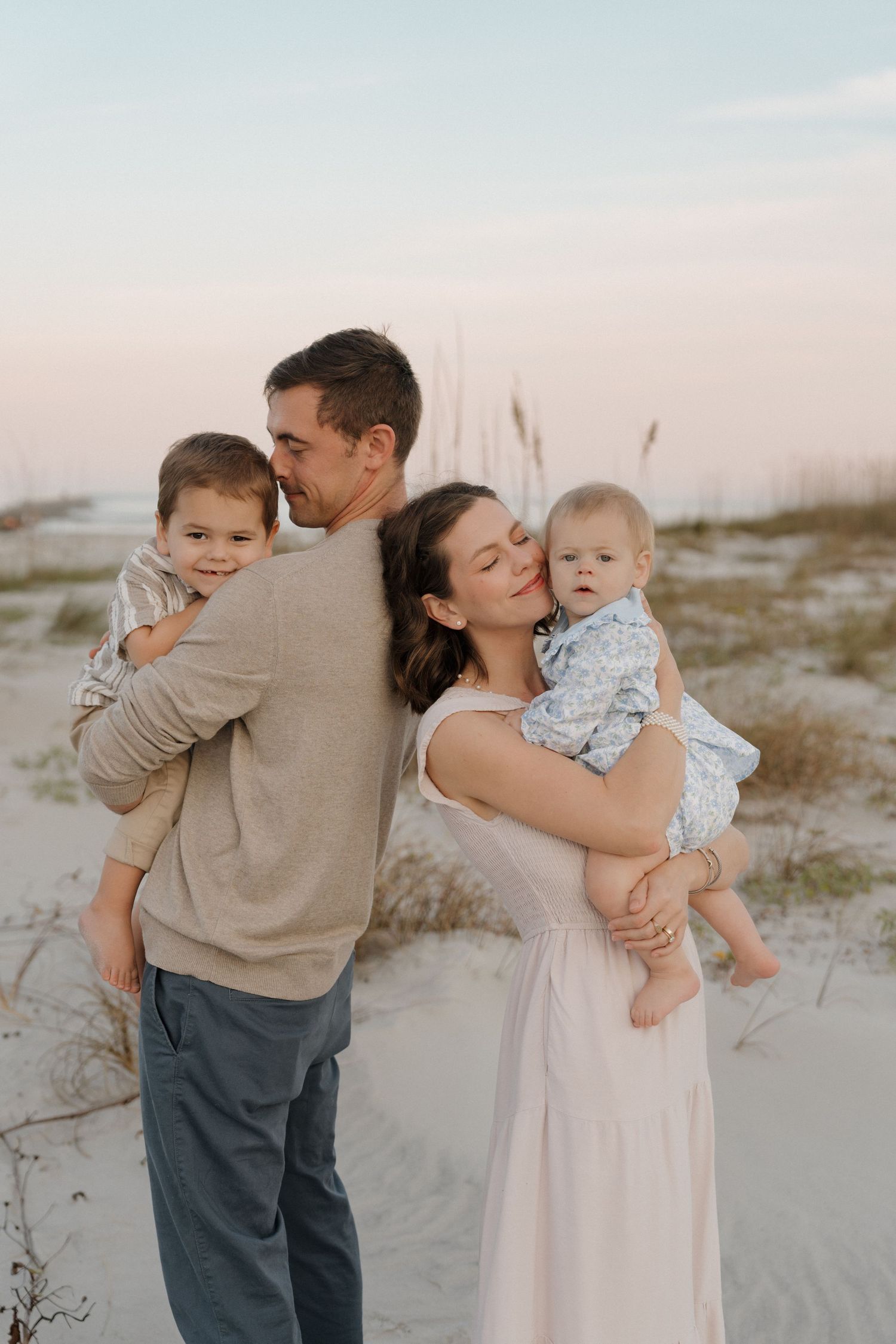 Family poses together by rustic wooden fence during golden hour photo session.