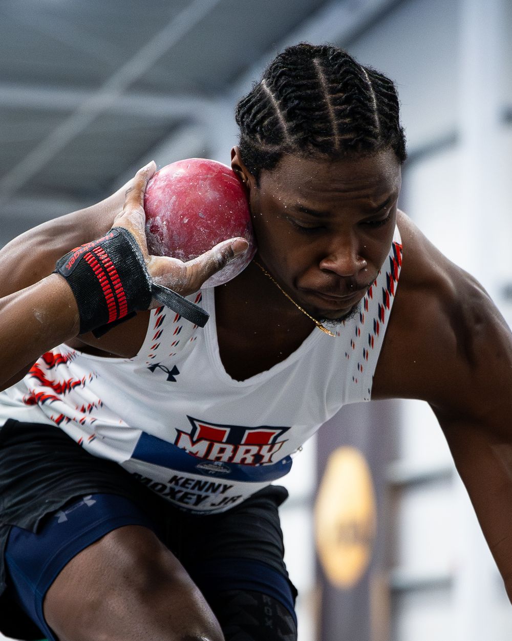 Athlete Kenny Doxey Jr. prepares to throw a shot put at an indoor track and field competition wearing a MARIC uniform.