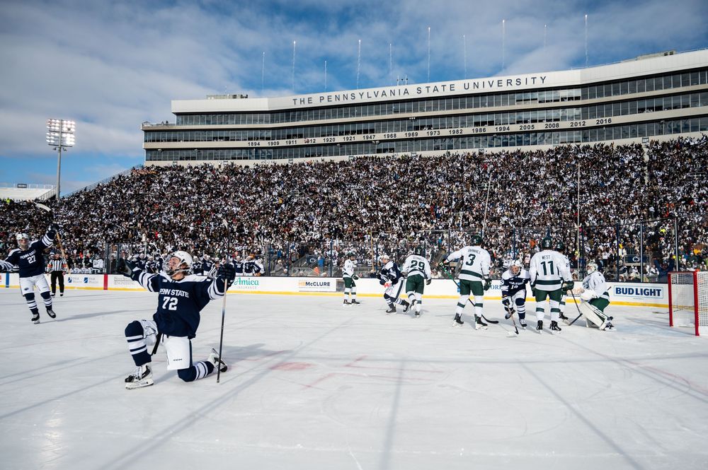 Hockey players compete during an outdoor NHL Winter Classic game in a packed stadium with snow-covered surroundings.