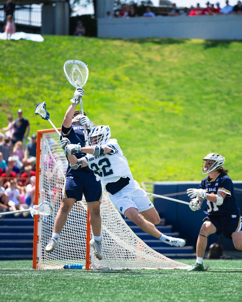 A sequence of photos showing a lacrosse goalie diving to make a save in front of the goal net on a grass field.