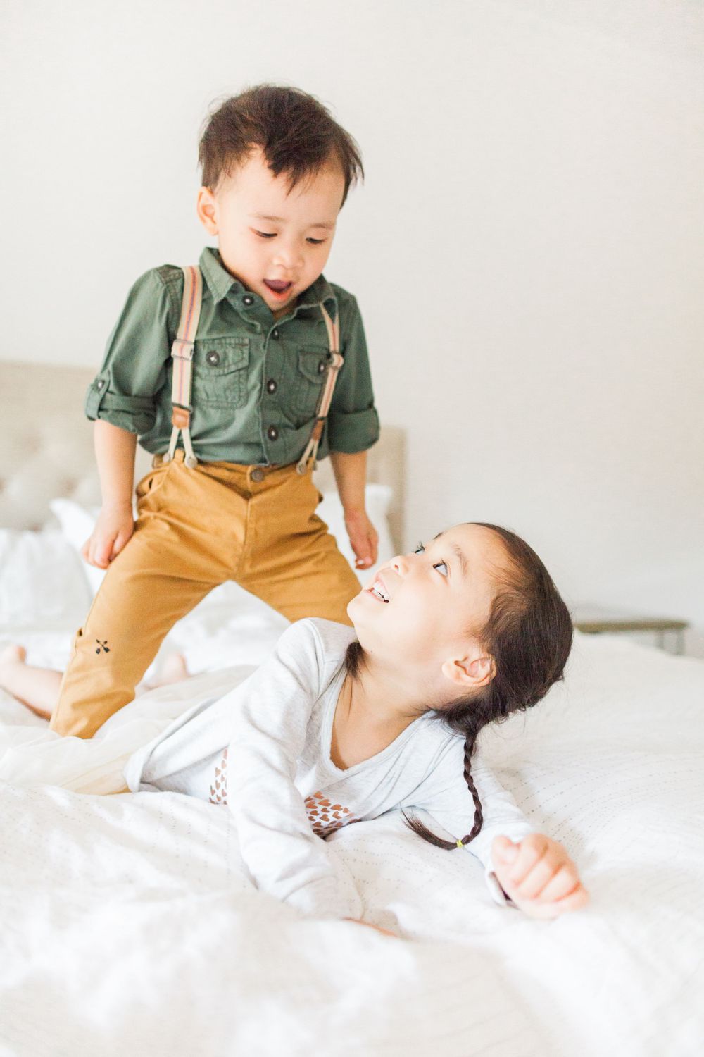 brother and sister playing on a bed together