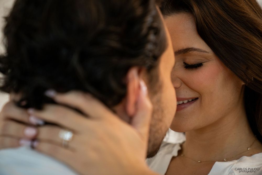 An intimate close-up moment between a couple with visible engagement ring.
