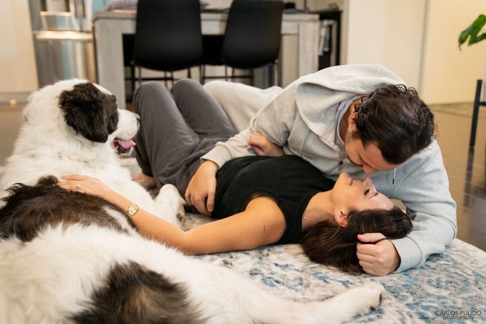 A couple relaxing on a bed with their black and white dog enjoying a peaceful moment together.