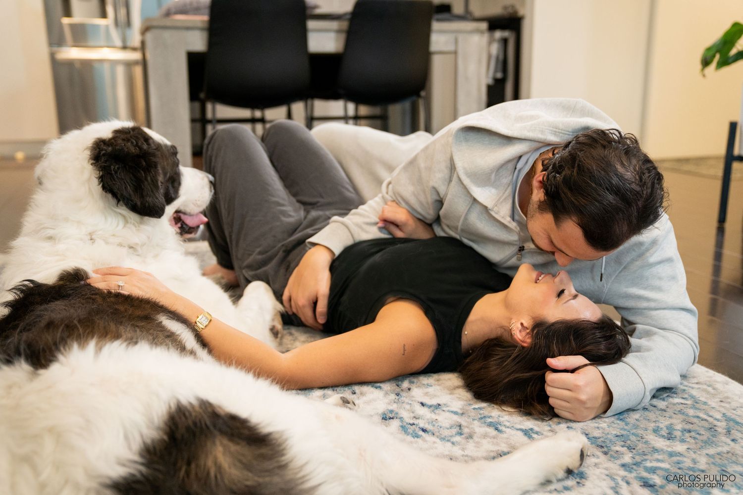 A couple relaxing on a bed with their black and white dog enjoying a peaceful moment together.