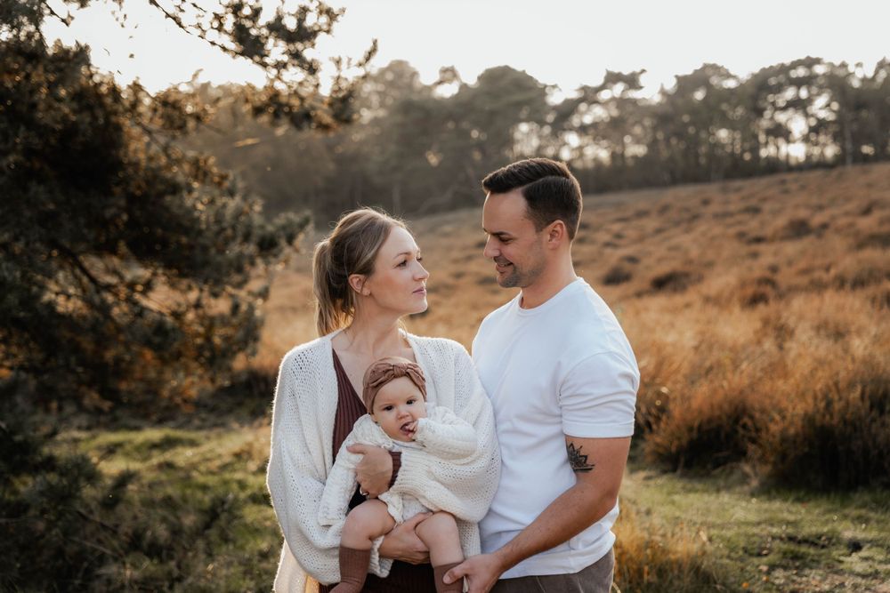 A loving family portrait at golden hour in a scenic outdoor meadow setting.