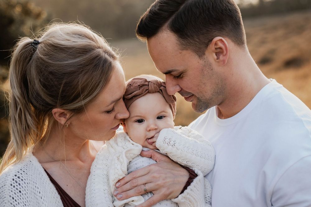An intimate family moment shared outdoors with a baby wearing a headband.